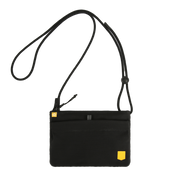 Black crossbody bag with a thin adjustable strap and a small yellow logo tab.