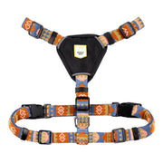 Colorful patterned dog harness with black chest pad and adjustable straps, featuring plastic buckles.